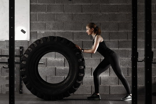 Fit female flipping tire at the gym.