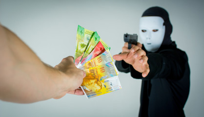 Mann mit einer Waffe bedroht jemanden und erhält Geld