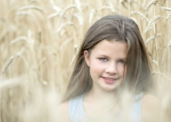 Little girl in golden wheat field in summer day. Portrait of a beautiful child. Concept of purity, growth, happiness