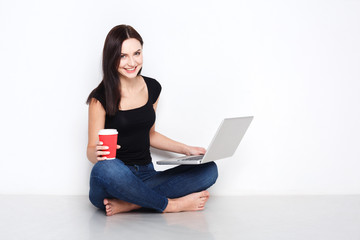Naklejka premium Woman using laptop sitting on the studio floor