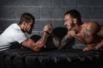 Two men with hands clasped in arm wrestling challenge. Bodybuilding concept