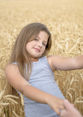 A pretty happy girl Holding the mother's hands in golden wheat field. Concept of purity, growth, happiness