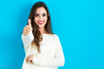 Happy young woman giving a thumb up on a blue background