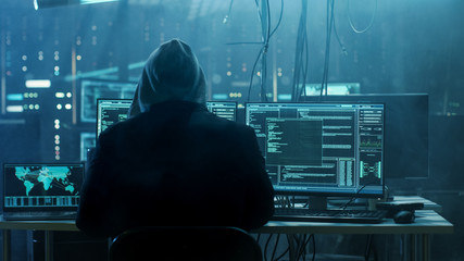 Dangerous Hooded Hacker Breaks into Government Data Servers and Infects Their System with a Virus. His Hideout Place has Dark Atmosphere, Multiple Displays, Cables Everywhere. - obrazy, fototapety, plakaty