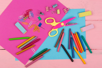 Back to school concept - school supplies: markers, crayons, pink and blue paper, scissors, eraser and other accessories
