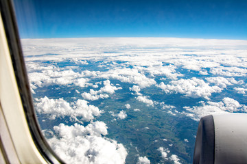 White clouds, the Earth and horizon viewed from a plane window