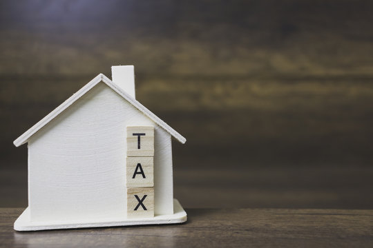 House model with tax word on wooden blocks