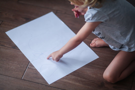 ребёнок рисует на листе бумаги 