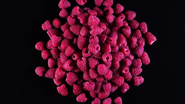 Fresh raspberries rotation in 4K.  Top view of fruits isolated on black background.
