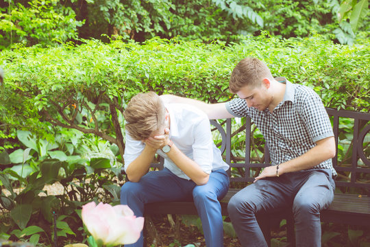 American Businessmen Consoling Friend. Frustrated Young Man Being Consoled By His Friend In Garden.