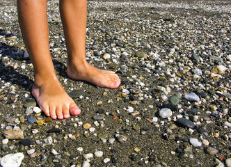Little feet on the beach. Legs of children stand on the beach