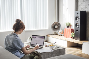 Beautiful ginger Caucasian woman using laptop and credit card for online shopping and sitting at home.