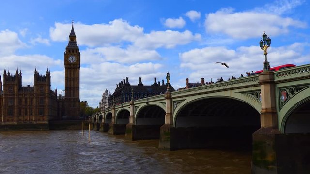 Iconic view of London-Westminster Bridge over river Thames with red bus and tourist crowds walking on it water birds in the sky, famous Big Ben or clock tower in the corner of Houses of Parliament, UK