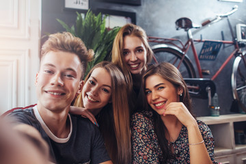 Young smiling teenagers taking selfie while having fun in stylish bar