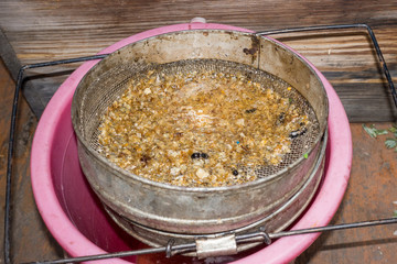 Strain the poured honey through a sieve. Filtering raw honey. Honey pouring through a sieve from honey extractor