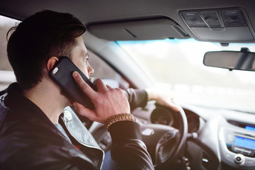 A man with a beard talking on a mobile phone in the car.