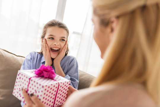 mother giving birthday present to girl at home