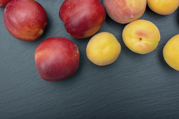 Ripe apricot and nectarine on black background of slate or stone