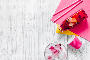 Bottle of fresh lemonade, fruits and ice cubes on wooden background top view copyspace