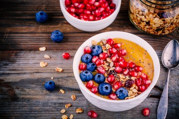 Healthy summer breakfast mango  smoothie bowl with granola, blueberries, pomegranate and chia seeds