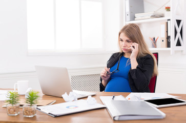 Pregnant business lady at work talking on phone