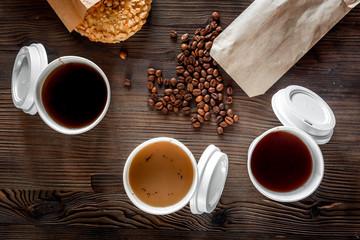 Coffee take out. Coffee cups with covers, coffee beans and cookies on wooden table backound top view