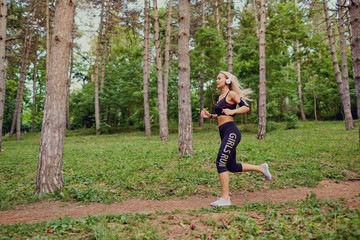 A woman runs jogging through the forest.