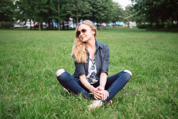 Fototapeta premium Portrait of Beautiful Sexy Blond Woman Sitting on the Grass. Good Sunny Day