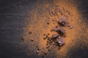 Chocolate background. Pieces and drops of chocolate, cocoa powder on black