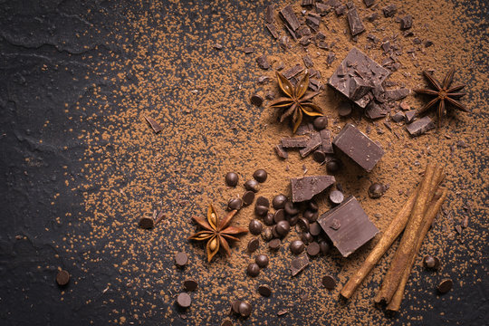Food dessert background. Pieces of dark chocolate, powder, drops and spices