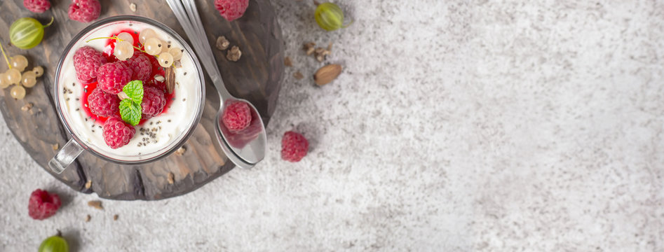 Summer healthy dessert with raspberries and yogurt on the cutting board. Banner format