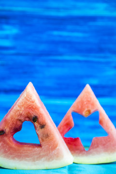 Triangular wedges of watermelon with carved figures on a blue background