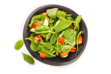 Salad with tomato, cucumber and spinach on the plate isolated on white background