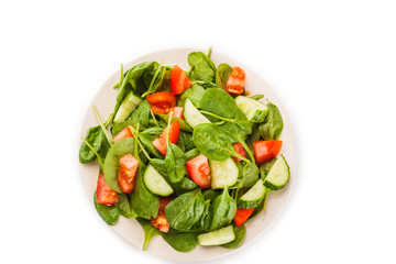 Salad with tomato, cucumber and spinach on the plate isolated on white background
