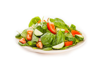 Salad with tomato, cucumber and spinach on the plate isolated on white background