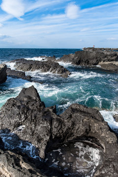 Rocky shoreline in Japan near Jogoshima Island during the sunny day time light house in the horizont