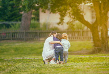 Togetherness.Mother with sons in park hugging each other