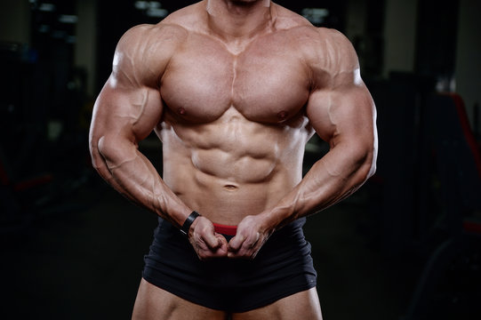 Brutal strong bodybuilder man pumping up muscles and train gym