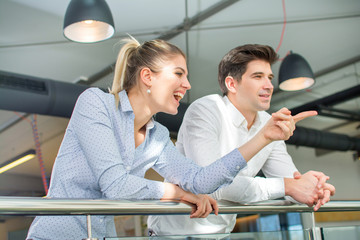 Businesswoman showing something to her male colleague during coffee break at office building.