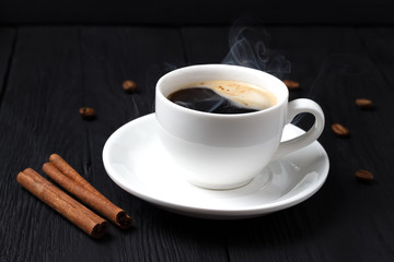 Hot coffee with foam in a white cup with cinnamon