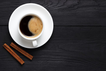 Hot coffee with foam in a white cup with cinnamon and place under the text