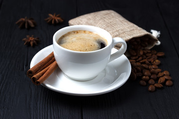 Coffee with foam in a white cup with anise and cinnamon.