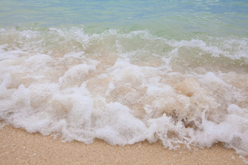 Abstract blurry background of soft wave of blue sea with sandy beach.