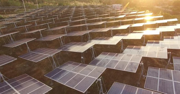 4K Aerial view of Solar Panels Farm (solar cell) with sunlight.Drone flight fly over solar panels field renewable green alternative energy concept in Thailand.