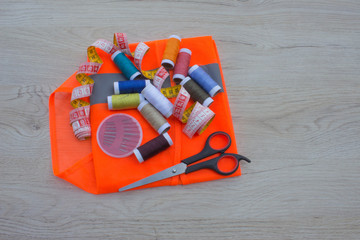 Sewing tools and sewing kit on wooden textured background. Thread, needles and cloth