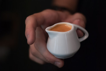A man's hand holds a small coffee pot with coffee