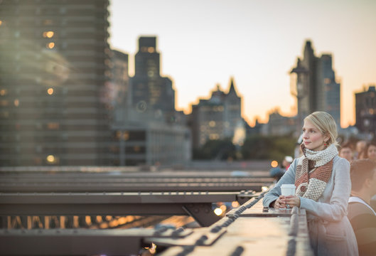 Woman on the Brooklyn Bridge Looking at Manhattan with a Coffee