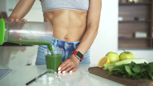 Fit woman drinking vegetable Green detox smoothie.  raw food diet