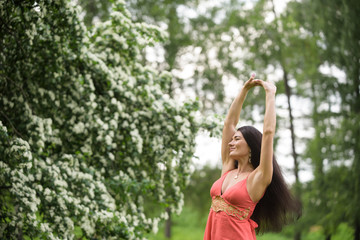 Happy girl stretching herself in park near blossoming tree