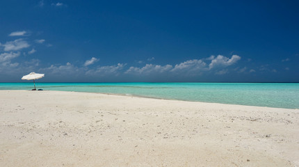 umbrella on idyllic tropical sand beach.White beach umbrella and blue sky.Sun and umbrella on the beach.Summer beach landscape .